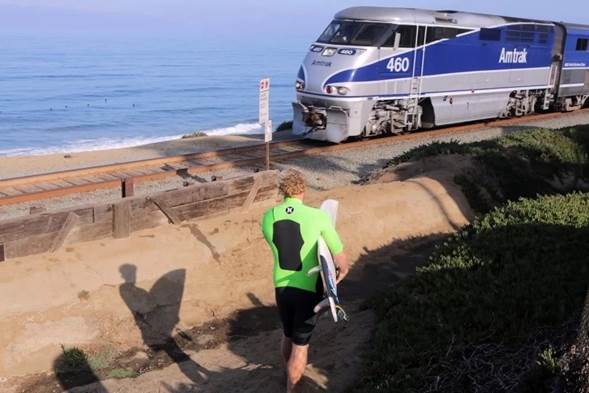 Un surfista se acerca a las vías del tren en Del Mar.